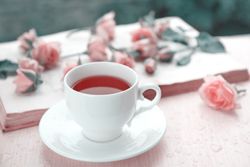 A cup of tea with pink flowers and open book