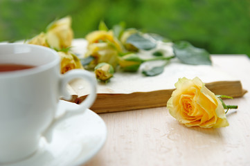 A cup of tea with yellow flowers and open book