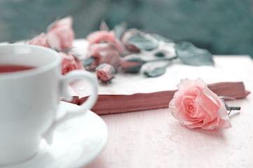 Fototapeta na wymiar A cup of tea with pink flowers and open book