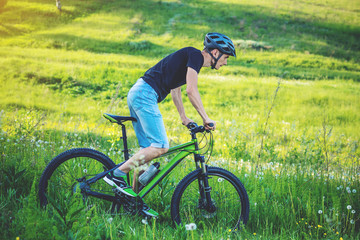 Man in a helmet riding on a green mountain bike in the woods among the trees. Active and healthy lifestyle