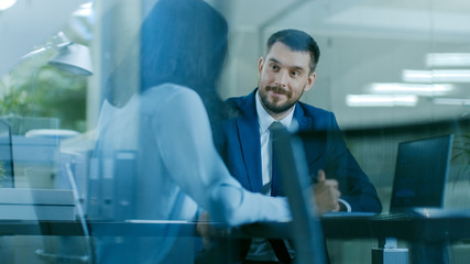Beautiful Female Manager has a Job Interview with a Businessman sitting at His Desk. Working on a Laptop in Modern Office.
