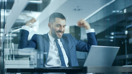 Handsome Businessman Works on a Laptop at His Desk, He Finished Job, Broke the Jackpot, Won Big and...