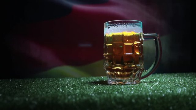 Creative concept. Pint of fresh beer on grass with blurred flag of Germany on background or Glass of lager beer ready for drink. Copy space. Selective focus