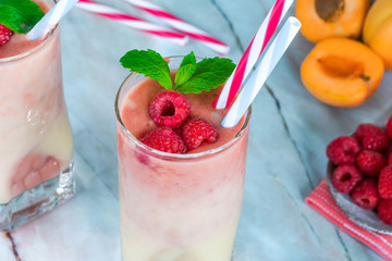Peach and raspberry melba smoothie garnished with fresh fruit and mint