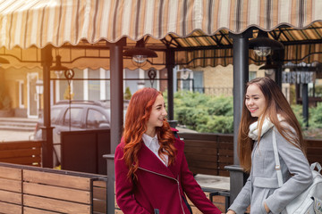 Two female teenagers embracing at the city street cafe