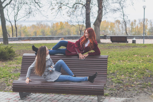 Female teenagers at the bench in an autumn city park