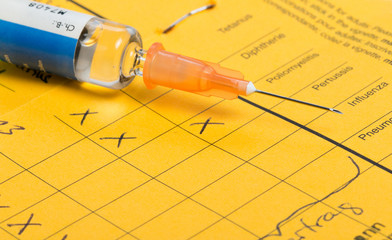 Syringe with vaccine, on vaccination certificate