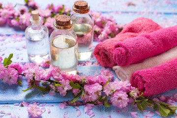 Fototapeta na wymiar Essential aroma oil, flowers and towels on blue wooden background.