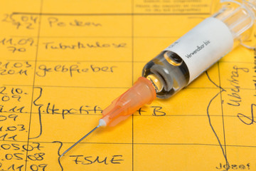 Syringe with vaccine, on vaccination certificate
