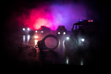 Closed handcuffs on the street pavement at night with police car lights