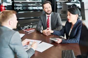 Business people having a meeting at auto salon. They are discussing a joint contract
