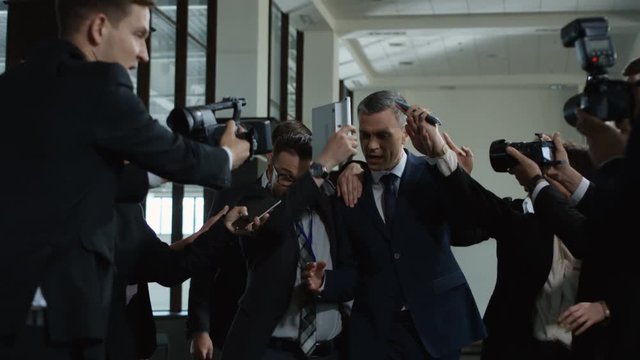 Annoyed formal man avoiding journalists and running away rejecting from interview and question answering