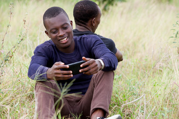 Portrait of two young men sitting back to back outdoors