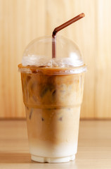 iced coffee latte in take away plastic glass on wooden background