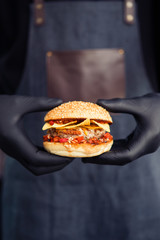 Burger holding in hands in black gloves
