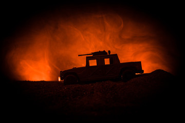 Military patrol car on dark toned foggy background. Army war concept. Silhouette of armored vehicle with gun in action. Decorated.
