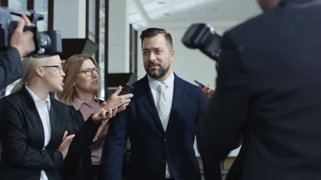 Adult formal man of government deputy talking to group of journalists and giving interview with smile looking excited with success
