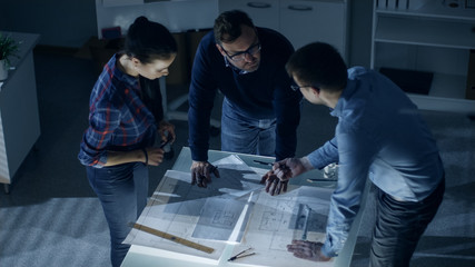 Late at Night Team of Design Engineers Work with Drafts and Documents on Illuminated Table.