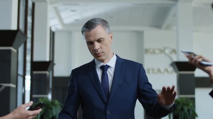Annoyed formal man avoiding journalists and running away rejecting from interview and question answering