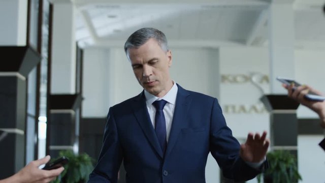 Annoyed formal man avoiding journalists and running away rejecting from interview and question answering