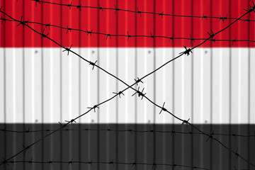 National flag of Iraq on fence. Barbed wire in the foreground symbolizes entry ban or prohibition for crossing border of country