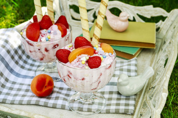 Ice cream dessert with fresh strawberries, peaches and crispy wafer rolls.