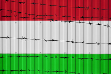 National flag of Hungary on fence. Barbed wire in the foreground symbolizes entry ban or prohibition for crossing border of country