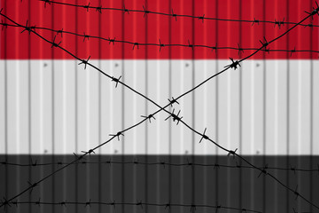 National flag of Yemen on fence. Barbed wire in the foreground symbolizes entry ban or prohibition for crossing border of country