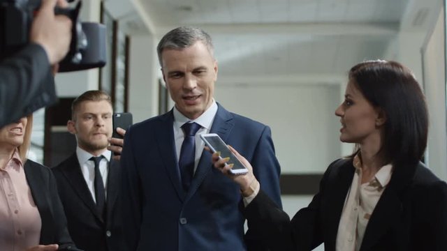 Adult formal man of government deputy talking to group of journalists and giving interview with smile looking excited with success