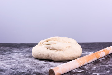 Fresh dough on the table with flour, and rolling pin