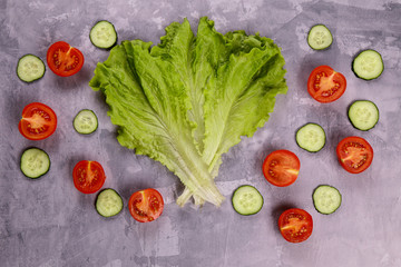 Naklejka na ściany i meble Assortment of fresh vegetables. Tomatoes, cucumbers and lettuce leaves on a concrete board