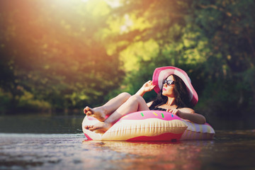Young woman floating in water enjoying and relaxing on sunny summer day. Retouched, filter applied, natural lighting.