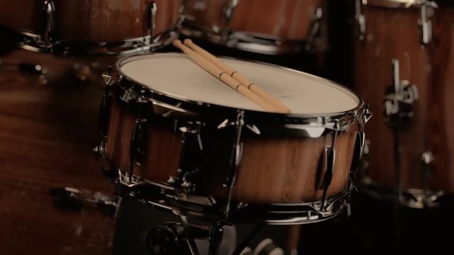 Pair of drumsticks on a snare drum. Camera slowly rotates around the kit. 4KHD