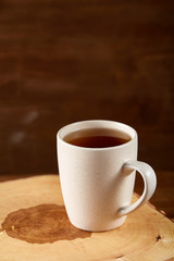 White cup of tea and cookies on a log over country style wooden background, close-up, selective focus