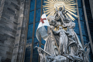 St. Stephen's statue with divinity, angel and flag outside of the the building St. Stephen's Cathedral the most largest church in Vienna, Austria.