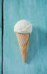 single vanilla ice cream in waffle scone on turquoise surface