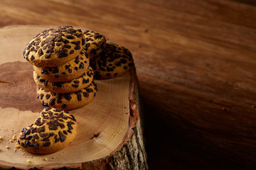 Sweet assortment of biscuits on a round wood log over rustic wooden background, close-up, selective focus.