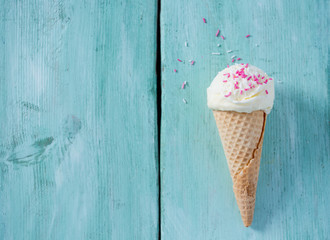 single vanilla ice cream in waffle scone on turquoise surface