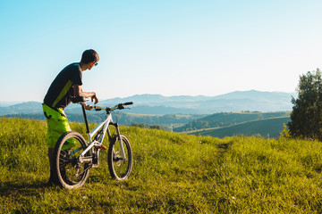 Obraz premium A cyclist on a mountain bike rises uphill. And looks at the scenic landscape.