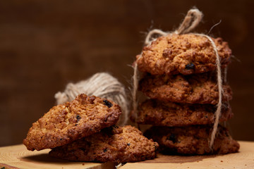 Bunch of chocolate biscuits on a round wood log over rustic wooden background, close-up, selective focus.