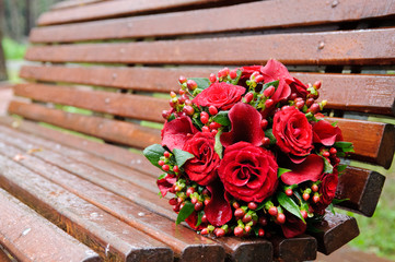 Beautiful wedding bouquet of the red roses on a brown bench. 