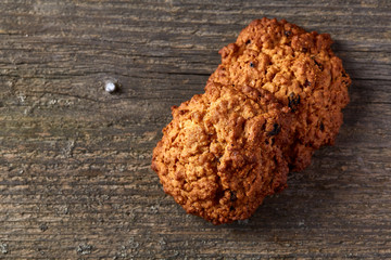 Bunch of chocolate biscuits on a round wood log over rustic wooden background, close-up, selective focus.