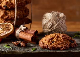 Christmas composition with chocolate biscuits, cinnamon and dried oranges on wooden background, close-up.