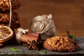 Christmas composition with chocolate biscuits, cinnamon and dried oranges on wooden background, close-up.