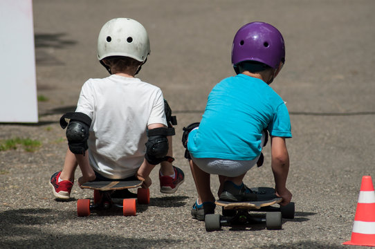 portrait of two boys sitting on skate board with helmet