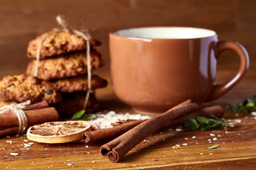 Christmas teatime with oatmeal, chocolate biscuits, and spices, on wooden background, close-up, selective focus.