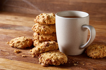 White porcelain mug of tea and sweet cookies on wooden background, top view, selective focus