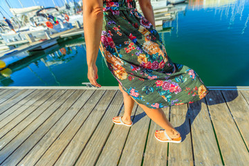 Detail of woman's legs walking on wooden jetty of Marina de Lagos on Algarve coast, Portugal, Europe. Lifestyle woman at the Bay of Lagos in summer holidays.