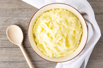 Пюре из картофеля в тарелке и деревянная ложка. Фон деревянный. Макро.