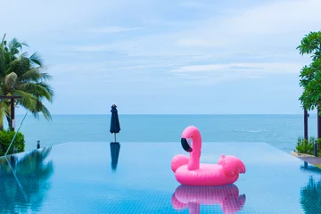 Fototapeten Flamingo-Floß schwimmt im Schwimmbad vor dem Meer und der Insel © Nattanee